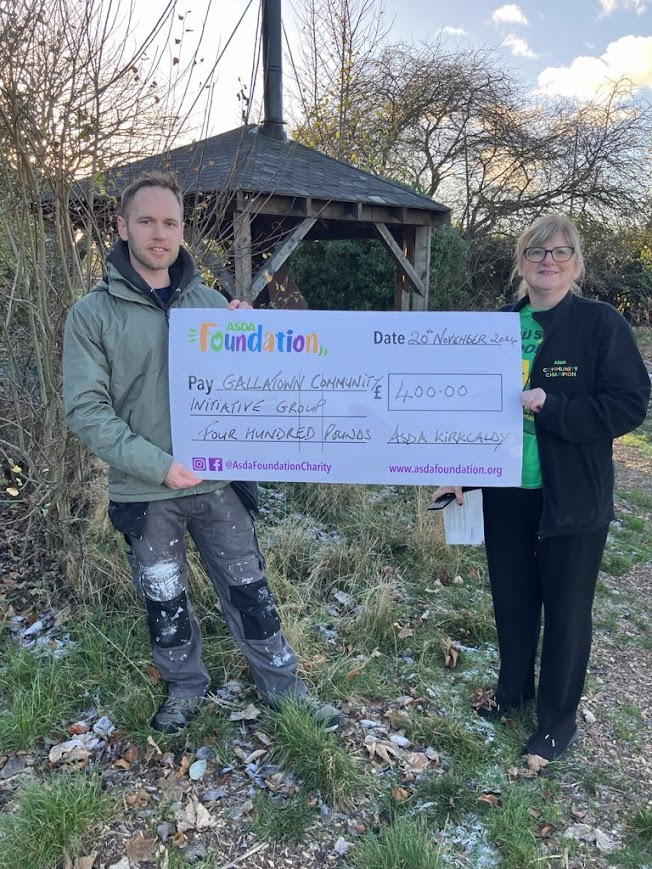 Ryan from Gallatown Community Initiative with Jean holding a giant £400 cheque from Asda Foundation